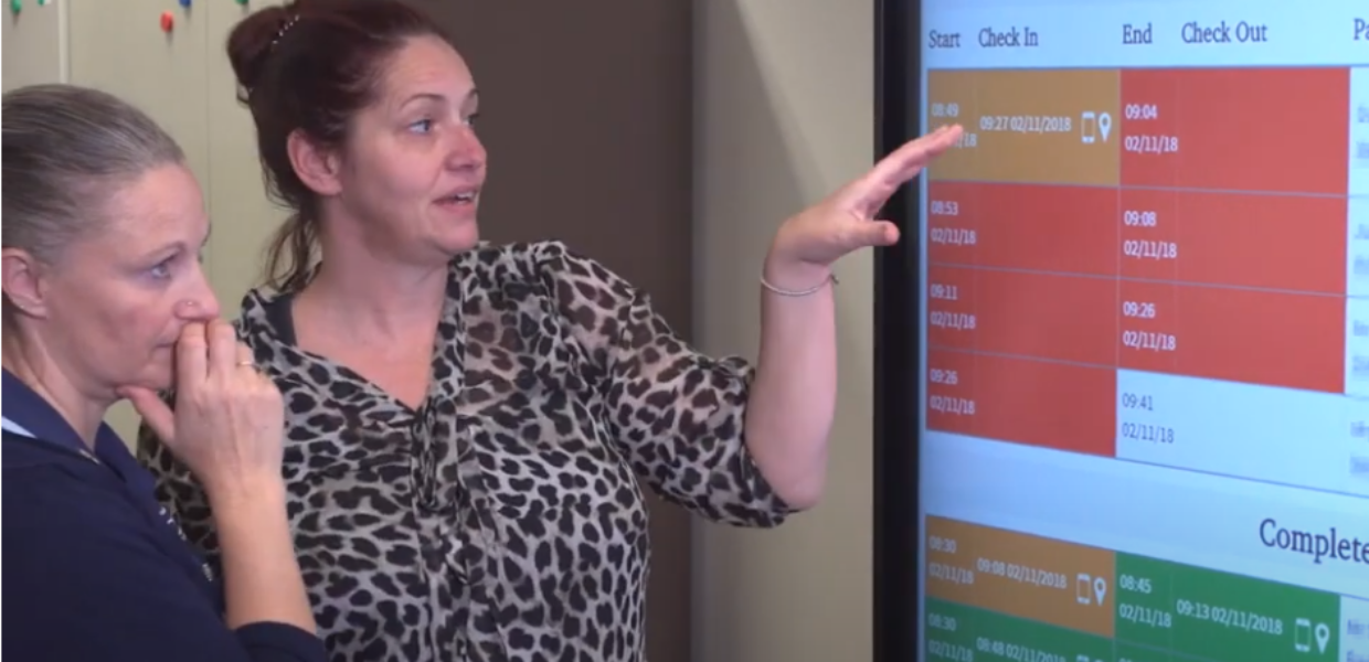 Staff looking at a digital screen showing rostering information