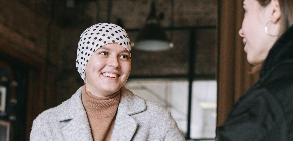 A smiling woman wearing a headscarf talks to her friend