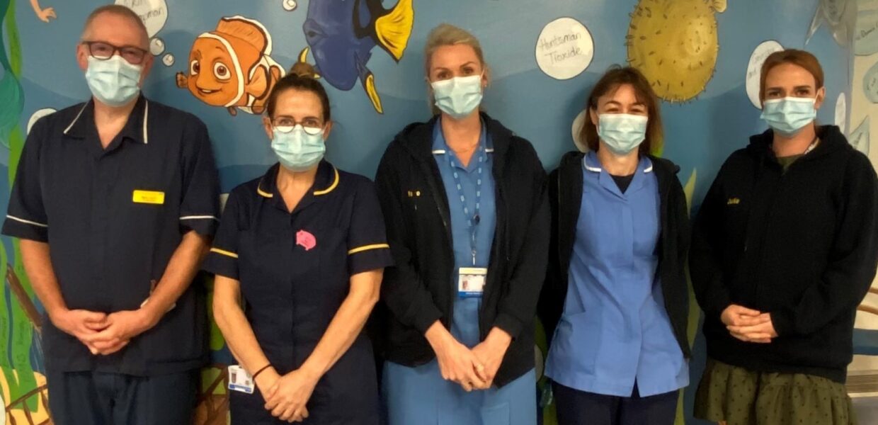 Staff from the Hospital at Home team stood in front of a wall