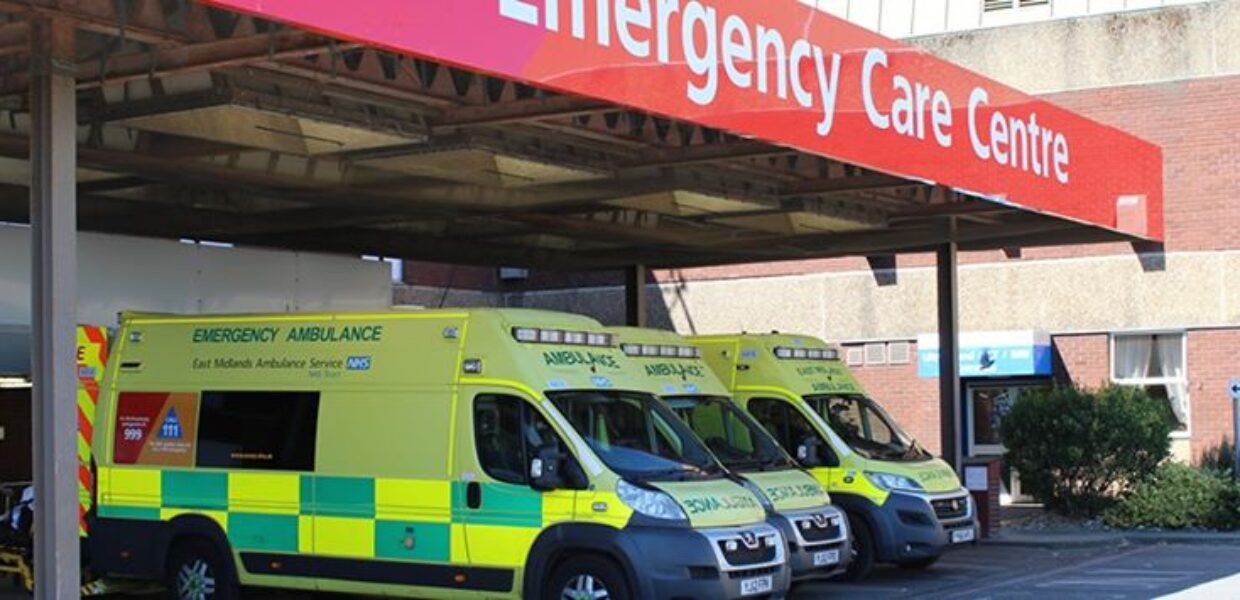 2 ambulances parked up under an emergency care centre sign