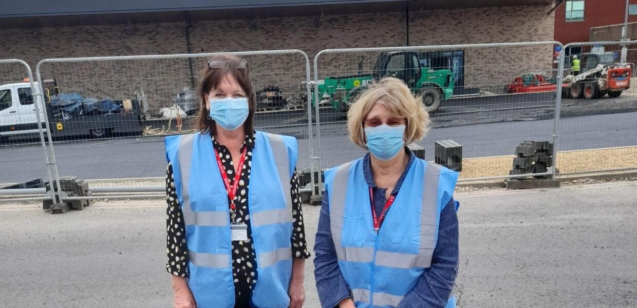 Volunteers Elaine and Jenny stood outside the new Emergency Department during its build