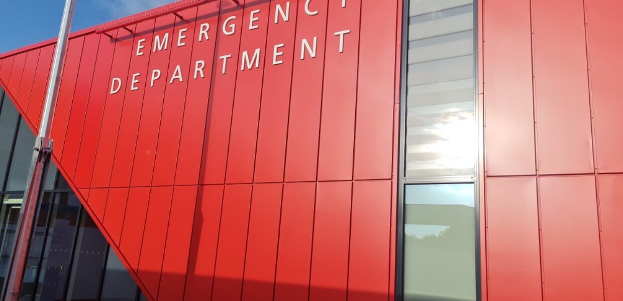 The exterior of the new Grimsby Emergency Department. The building is clad in red and has floor to ceiling windows surrounding the door